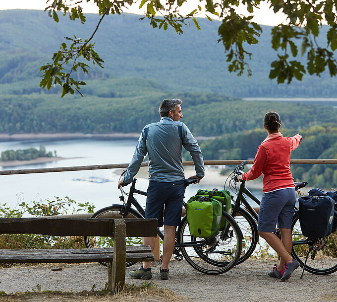 Zwei Personen mit Fahrrad an einer Bank